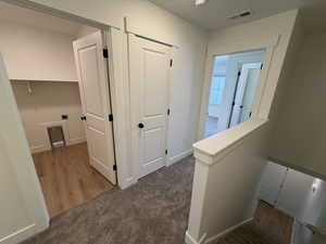 Hallway with an upstairs landing and dark carpet