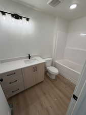 Full bathroom with vanity, light wood-style flooring, a textured ceiling, and tub / shower combination