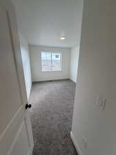 Carpeted spare room featuring baseboards
