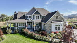 Craftsman-style home featuring stone siding, covered porch, a chimney, and a standing seam roof