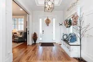 Entrance foyer featuring hardwood / wood-style floors, a tray ceiling, a chandelier, and a wainscoted wall