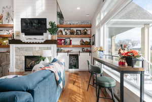 Bar with wood finished floors and a stone fireplace