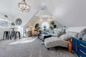 Carpeted living room with vaulted ceiling and a chandelier