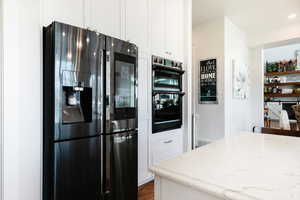 Kitchen with fridge with ice dispenser, white cabinetry, and dark wood-style flooring