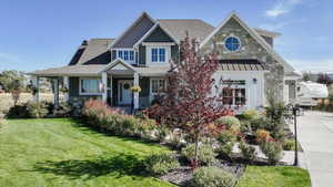 View of front facade with a front lawn, a porch, a standing seam roof, stone siding, and a metal roof