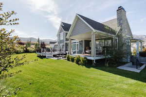 Back of property with a deck with mountain view, a yard, a chimney, and a shingled roof