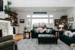 Living room featuring a fireplace, healthy amount of natural light, light wood-style floors, recessed lighting, and crown molding