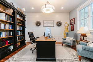 Office with dark wood-style flooring, recessed lighting, and wood walls