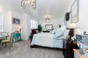 Carpeted bedroom with a chandelier and baseboards