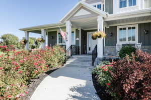 View of exterior entry featuring board and batten siding, a porch, and stone siding