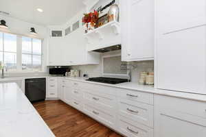 Kitchen featuring white cabinetry, glass insert cabinets, black appliances, dark wood-type flooring, and light stone countertops