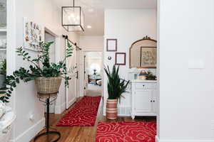 Hall with dark wood-type flooring, a chandelier, and a barn door