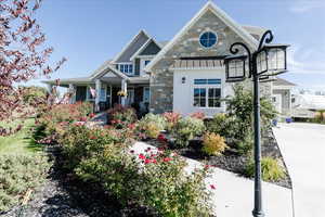 View of front of property with covered porch, stone siding, a standing seam roof, and a metal roof