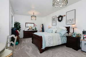 Bedroom with a chandelier and light colored carpet