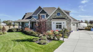 Craftsman inspired home with a front yard, a standing seam roof, stone siding, a metal roof, and concrete driveway