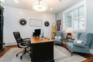 Home office with dark wood finished floors, recessed lighting, and wooden walls