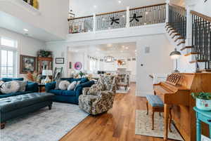 Living area with hardwood / wood-style floors, a towering ceiling, stairway, and recessed lighting