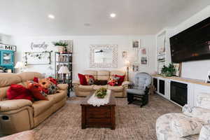 Carpeted living room featuring recessed lighting and a fireplace