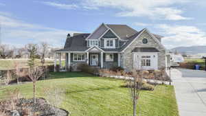 Craftsman inspired home with a front lawn, stone siding, a chimney, concrete driveway, and a standing seam roof