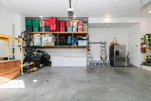 Garage with stainless steel refrigerator with ice dispenser and a garage door opener