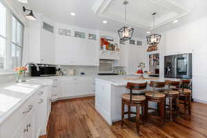 Kitchen featuring decorative light fixtures, a breakfast bar area, white cabinetry, a center island, and light wood-type flooring