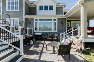 Rear view of house with a patio area, stairway, and board and batten siding