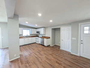 Kitchen featuring stainless steel appliances, white cabinets, dark wood-style flooring, recessed lighting, and lofted ceiling