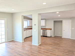 Kitchen featuring white cabinets, recessed lighting, light wood finished floors, stainless steel dishwasher, and butcher block counters