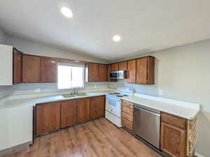 Kitchen with appliances with stainless steel finishes, light countertops, recessed lighting, dark wood finished floors, and lofted ceiling