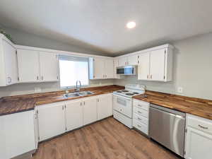 Kitchen with stainless steel appliances, white cabinets, wood counters, and dark wood-style floors