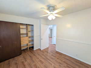 Bedroom with a textured ceiling, a ceiling fan, dark wood finished floors, and a closet