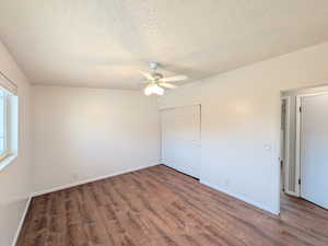 Unfurnished bedroom with a textured ceiling, wood finished floors, ceiling fan, and a closet