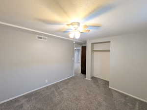 Unfurnished bedroom featuring a textured ceiling, carpet flooring, ceiling fan, and a closet