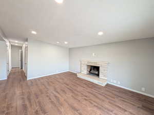 Unfurnished living room featuring recessed lighting, a fireplace, and dark wood finished floors