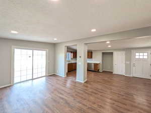 Unfurnished living room with recessed lighting, a textured ceiling, and dark wood-style floors