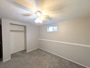 Unfurnished bedroom with a textured ceiling, carpet floors, a closet, and ceiling fan