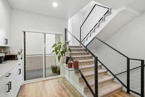 Stairway featuring wood finished floors and recessed lighting