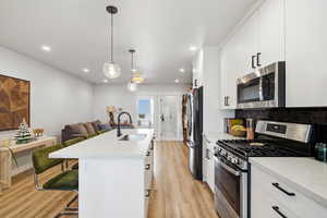 Kitchen featuring appliances with stainless steel finishes, a breakfast bar area, hanging light fixtures, light stone counters, and recessed lighting