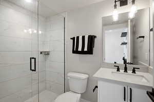 Bathroom featuring vanity and a marble finish shower