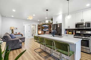 Kitchen featuring appliances with stainless steel finishes, a kitchen bar, recessed lighting, white cabinetry, and decorative backsplash