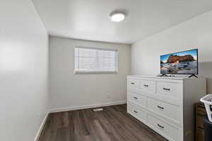 Bedroom featuring dark wood-style floors and baseboards