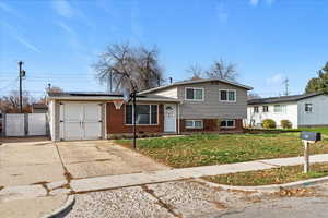 Tri-level home featuring solar panels, brick siding, and a gate