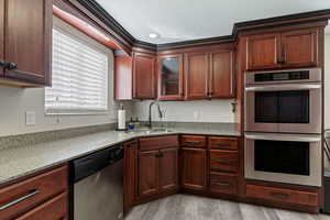 Kitchen featuring stainless steel appliances, light stone counters, glass insert cabinets, and light wood-style floors