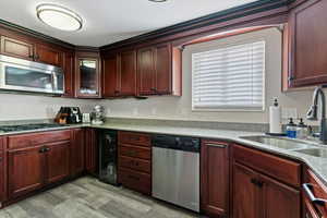 Kitchen featuring stainless steel appliances, light stone counters, beverage cooler, light wood-type flooring, and glass insert cabinets