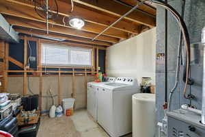 Laundry room with separate washer and dryer, concrete flooring, and heating unit
