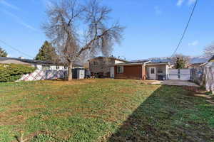 Rear view of property featuring roof mounted solar panels, a shed, a fenced backyard, and a patio area