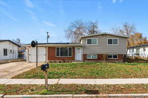 Tri-level home with roof mounted solar panels, brick siding, and a front yard