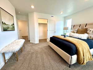 Carpeted bedroom with a textured ceiling, a walk in closet, and recessed lighting
