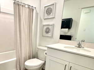 Bathroom featuring vanity, shower / bathtub combination with curtain, and dark wood-style flooring