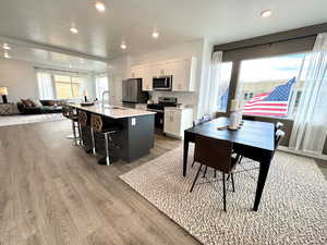Kitchen featuring open floor plan, stainless steel appliances, a kitchen island with sink, recessed lighting, and white cabinets